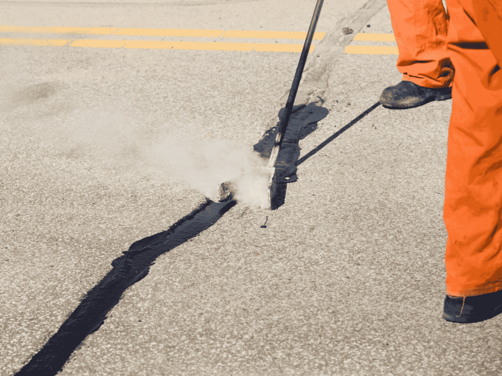 Road crew sealing asphalt cracks with hot tar to prevent further pavement damage in Jacksonville, TX.