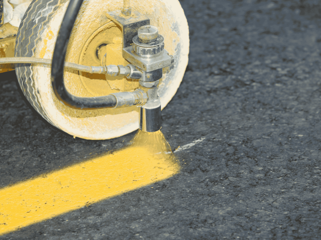 Close-up of a line striping machine painting bright yellow road markings for improved traffic safety and organization in Jacksonville, TX.